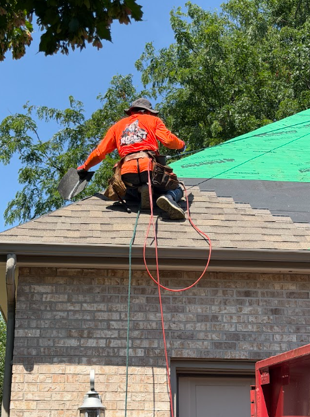 Roofer in a Rocket Roofing shirt working along the ridge of a shingled roof