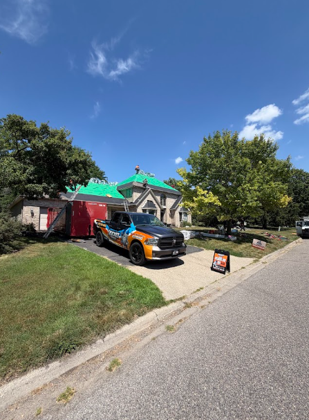 Home with fresh underlayment down and a Rocket Roofing truck and yard sign out front