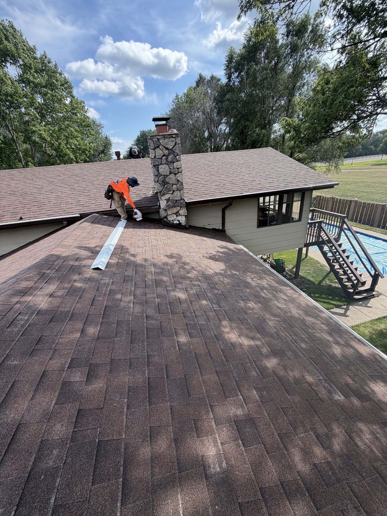 Rocket Roofing crew member finishing chimney flashing on a shingled roof