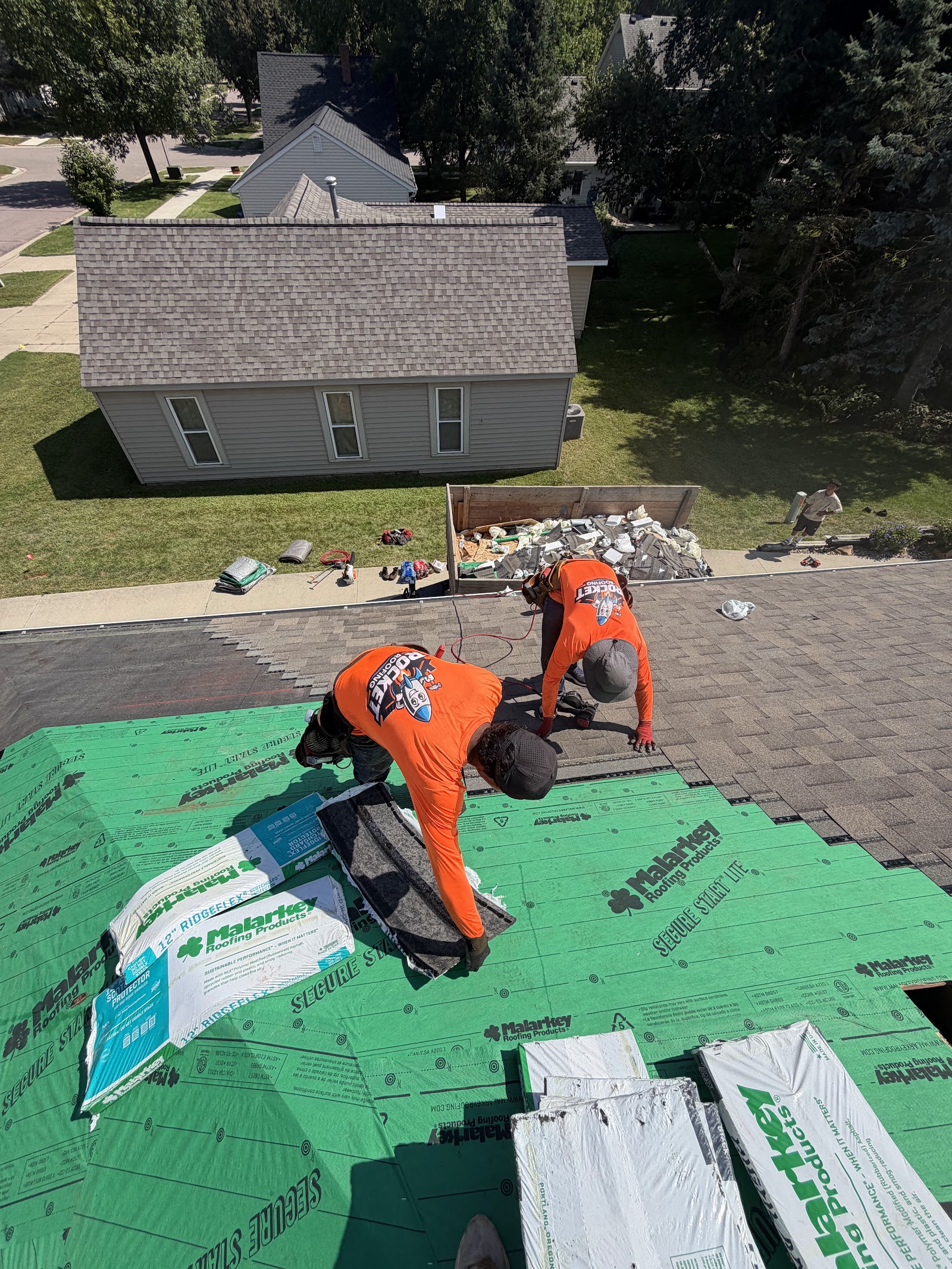 Aerial view of a finished tear-off with dumpster and crew wrapping up the job