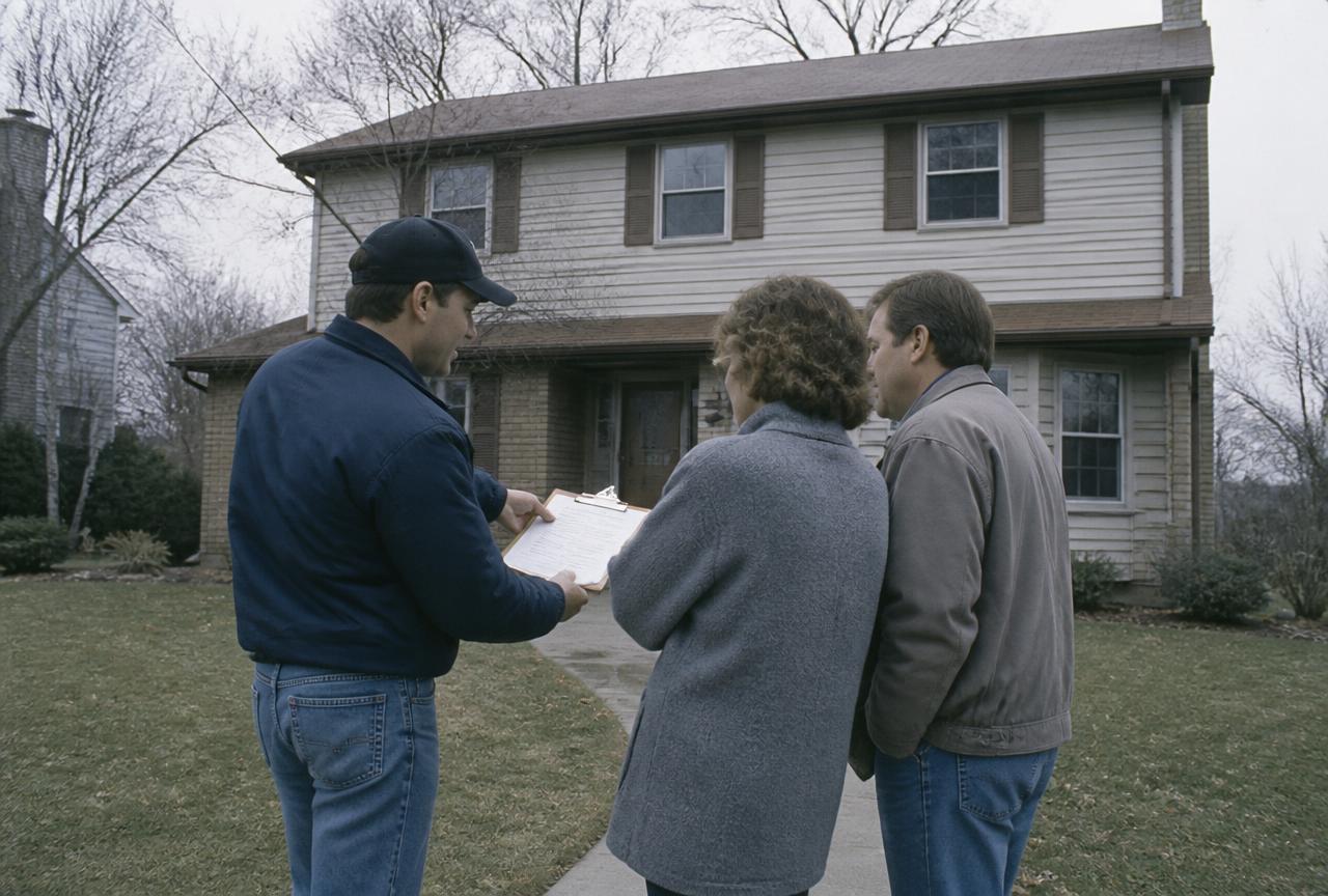 Roofing contractor reviewing an estimate with homeowners on a suburban front porch